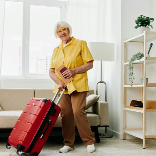 Happy senior woman with passport and travel ticket packed a red suitcase, vacation and health care