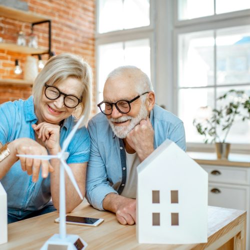 Senior couple with house models and toy wind turbine at home