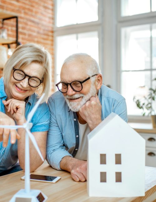 Senior couple with house models and toy wind turbine at home