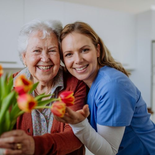 Senior woman and nurse with tulip bouquet.