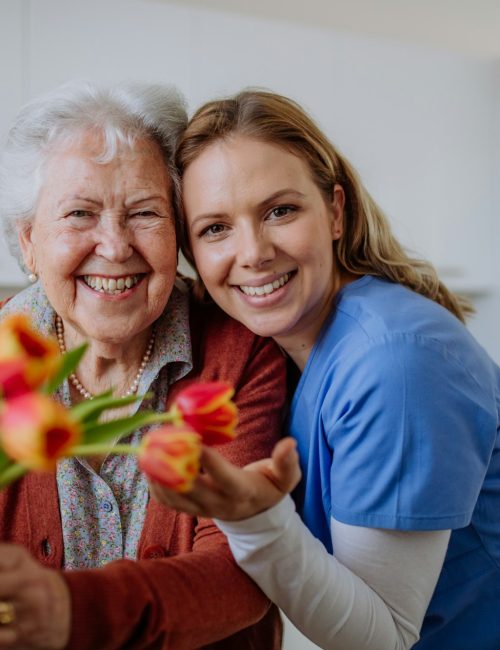 Senior woman and nurse with tulip bouquet.