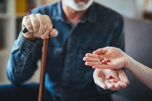 An elderly man prepares to take a pill with a glass of water, illustrating the importance of following a consistent medication schedule for senior health and safety.