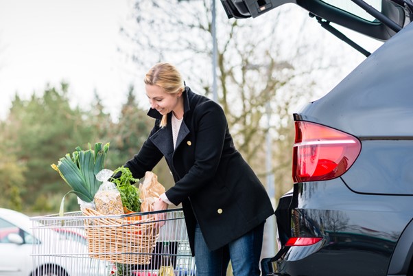 A woman loads groceries into her car from a shopping cart, representing everyday concierge services that can provide essential support for seniors managing errands and independence.