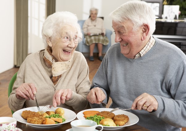 A joyful senior couple enjoys a healthy meal together, representing food ideas that support brain health and nutrition for older adults.