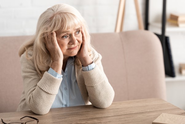 An elderly woman sits alone with a distressed expression, symbolizing the confusion and agitation often experienced during sundowning syndrome—and the support home care professionals can provide.