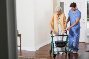 Young caregiver offering respectful support to an elderly woman using a walker, highlighting the importance of dignity and boundaries in senior care.