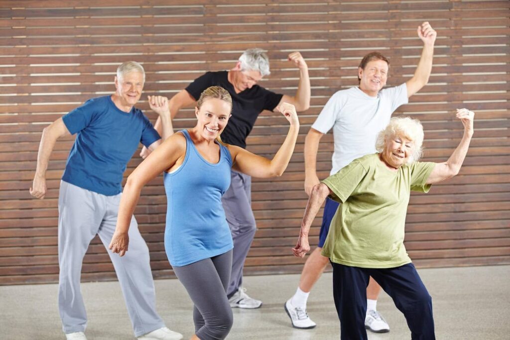 Group of seniors and an instructor dancing energetically in a Zumba class, highlighting fun, movement, and joint health benefits for older adults.