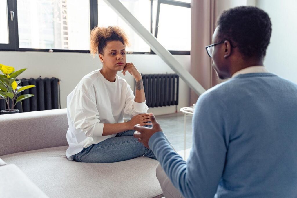 Two siblings having a serious conversation in a modern living room, representing a discussion about home care decisions for a family member.