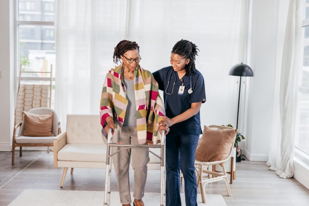 Caregiver supporting an elderly woman with a walker, showing how personal care services change from light help to full assistance.