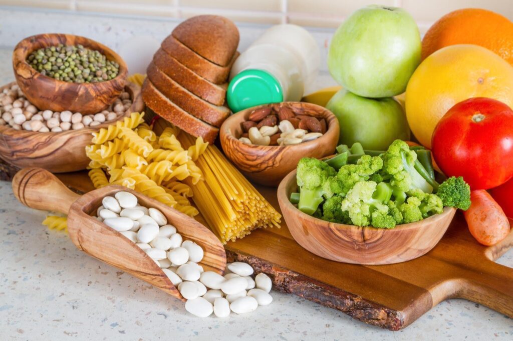 Healthy variety of fruits, vegetables, nuts, pasta, and beans displayed on a kitchen counter, representing nutrients seniors often miss in daily diets.