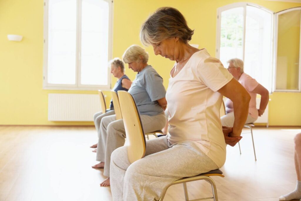 Seniors participating in an accessible Zumba class with seated exercises, showing that fitness can be adapted for every mobility level.