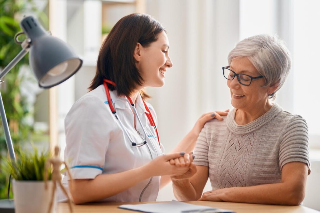 Senior woman smiling as a caregiver offers support, showing that asking for help is not embarrassing but a respectful and caring experience.
