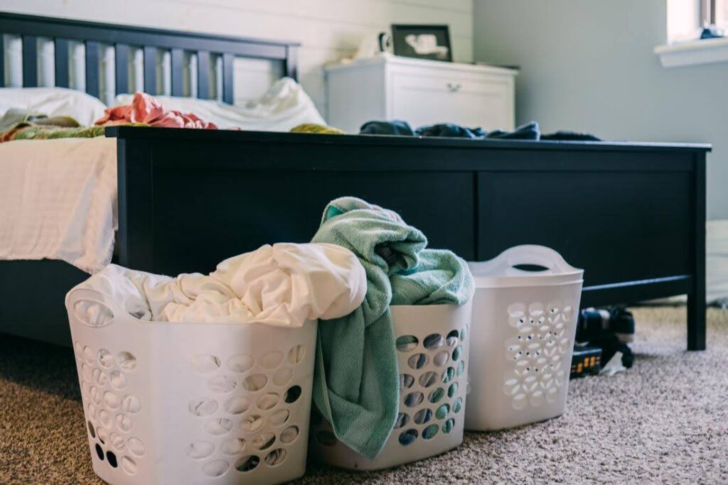 Overflowing laundry baskets filled with clothes in a bedroom, illustrating why seniors often struggle with laundry and need supportive care.