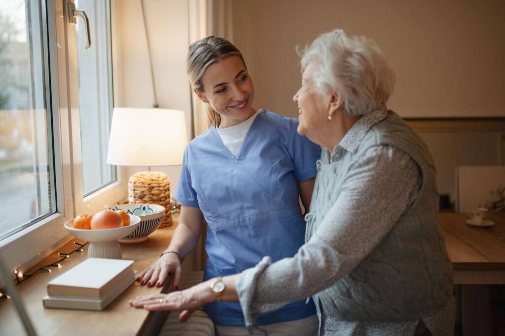 A compassionate caregiver providing company and emotional support to an elderly woman at home, representing the deeper purpose of companion care by Ace Home Care.