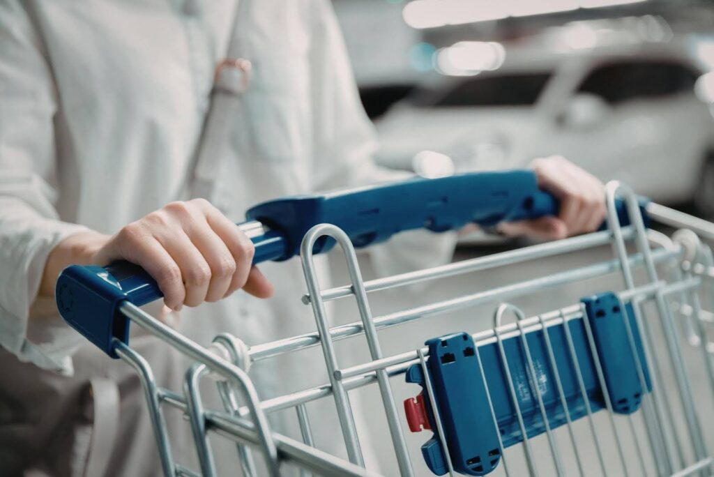 A caregiver helping a senior with daily errands, pushing a shopping cart in a store parking area as part of Ace Home Care’s non-medical support services.