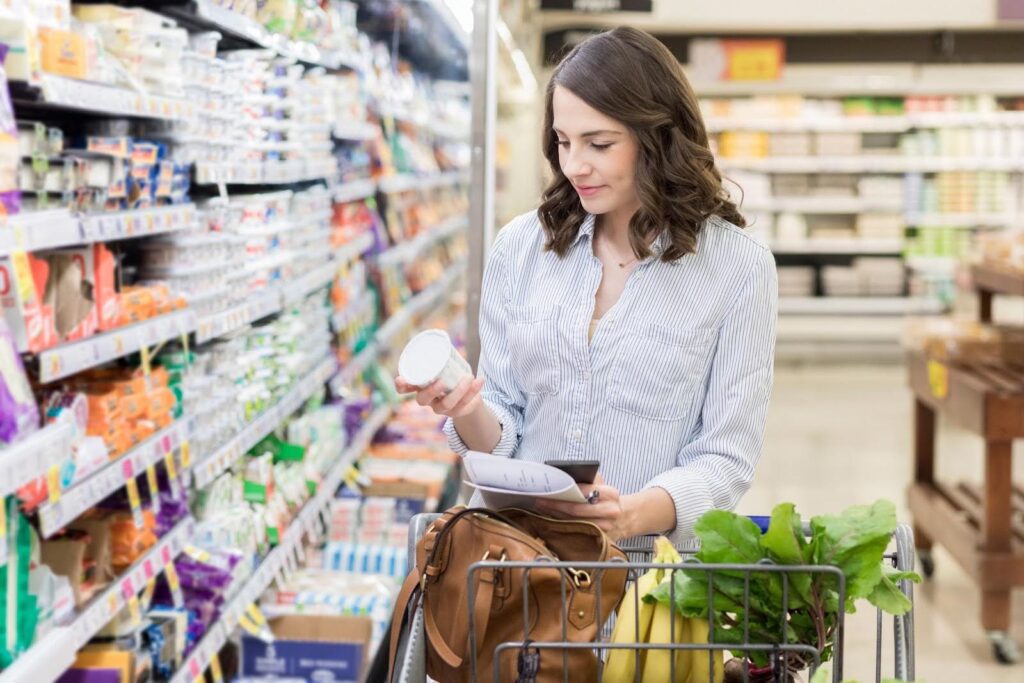 Woman shopping for groceries and checking a list, representing the personalized errands and support offered through senior concierge services.