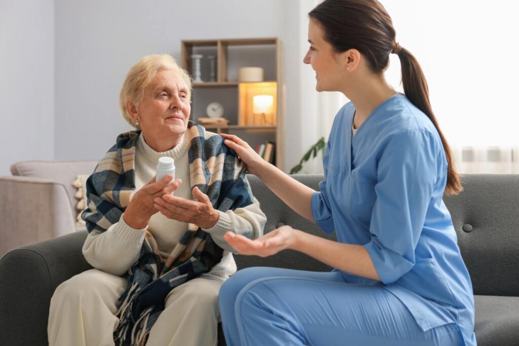 Caregiver talking with a senior woman holding medication, illustrating the transition from assisted living to personalized in-home care.
