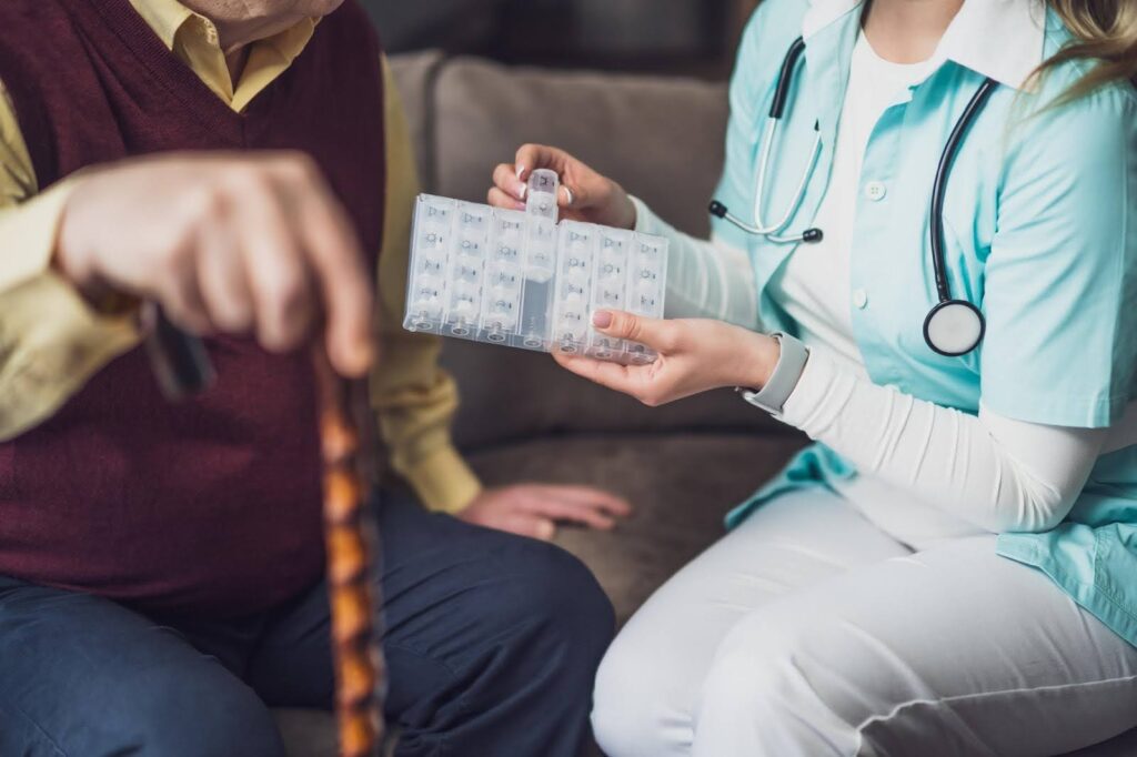 Caregiver providing a medication reminder to a senior with a pill organizer — medication reminder services explained.