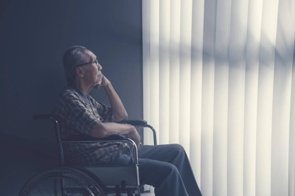 Senior sitting alone in a wheelchair by a window, illustrating clinical loneliness and how Ace Home Care provides emotional support for seniors.