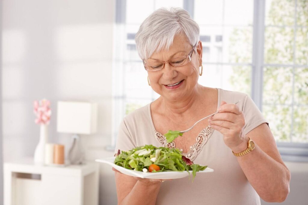 Senior woman enjoying a healthy meal indoors during cold weather, highlighting how Ace Home Care supports proper nutrition for seniors when colder temperatures change dietary needs.