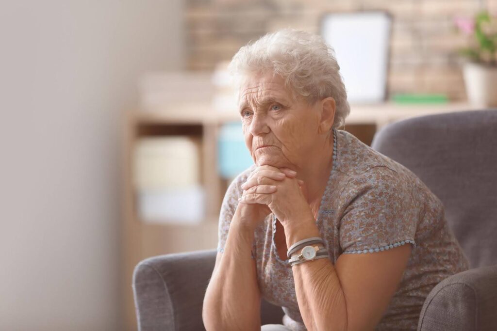 Elderly woman sitting thoughtfully at home, reflecting on caregiving guilt and the decision to accept outside help with compassionate support from Ace Home Care.