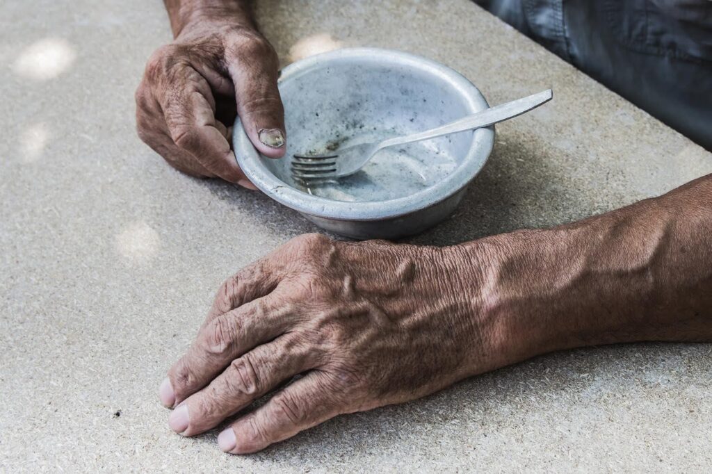 Ace Home Care highlighting signs of a tired senior affected by undernourishment, showing elderly hands beside an empty bowl to reflect nutritional deficiency and fatigue in older adults.
