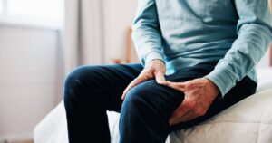 Ace Home Care providing compassionate support for seniors with osteoporosis, showing an older adult experiencing knee pain and mobility challenges in a home setting.