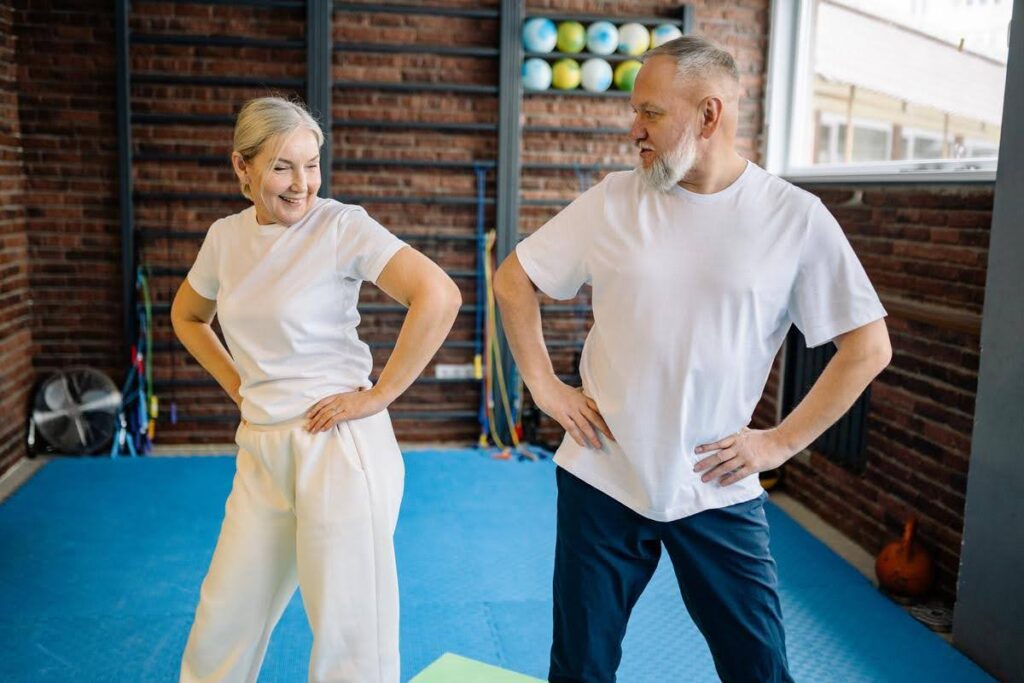 Senior couple exercising together in a fitness studio, demonstrating safe physical activity for older adults with Osteopenia supported by wellness guidance from Ace Home Care.