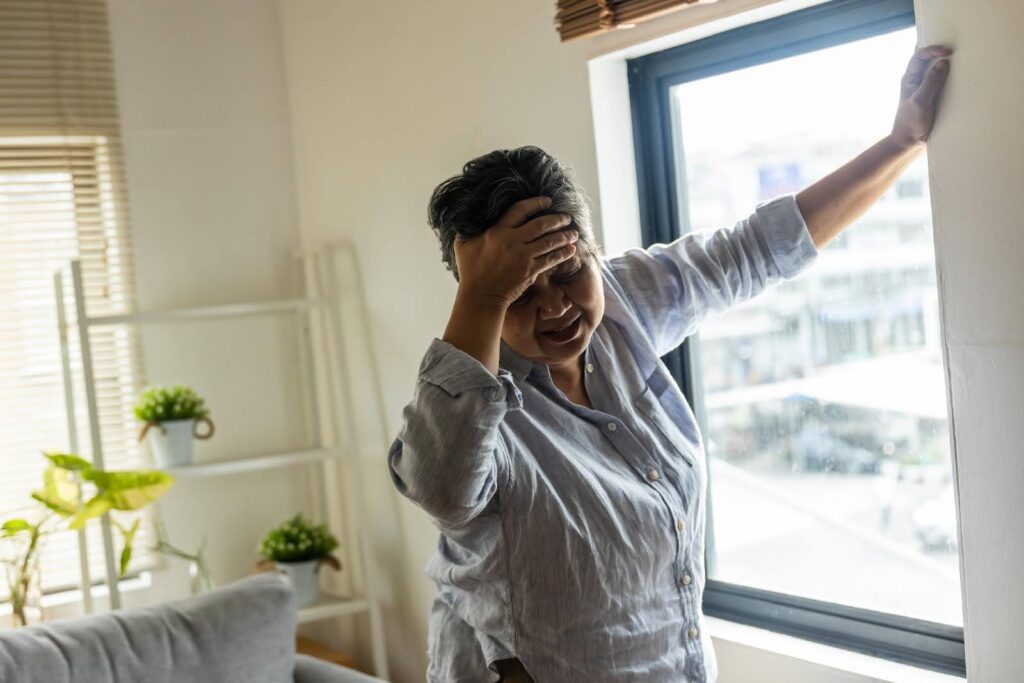 Senior experiencing Vertigo and dizziness at home while holding her head for balance, highlighting supportive care services provided by Ace Home Care.