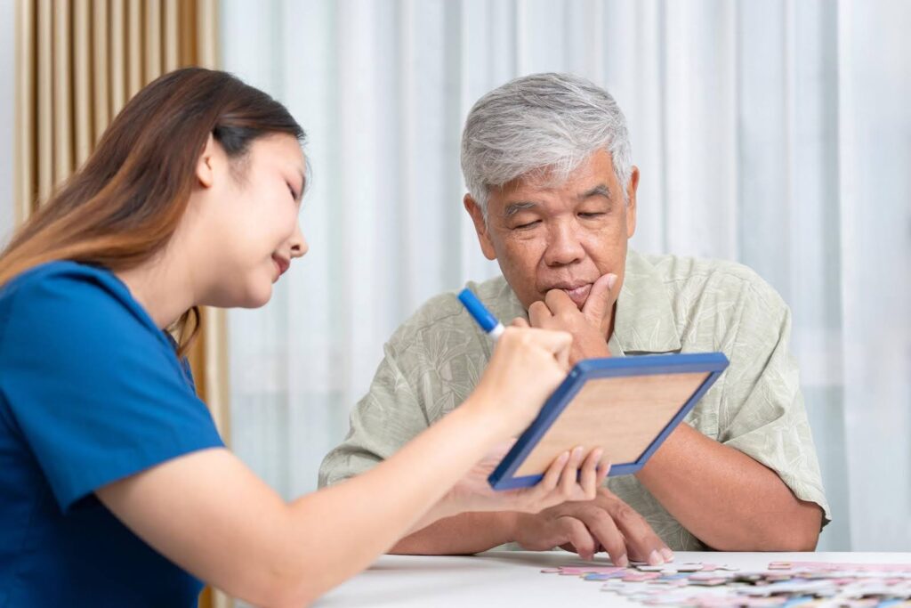 Caregiver assisting a senior with a cognitive activity, illustrating early signs of Paranoia or cognitive decline and supportive care services from Ace Home Care.