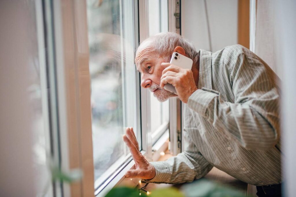 Elderly man showing signs of frailty while looking out the window, supported by Ace Home Care