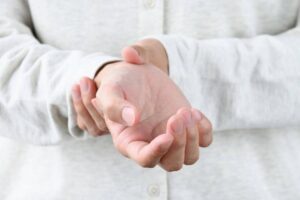 Close-up of hands showing tremors in an elderly person receiving support from Ace Home Care
