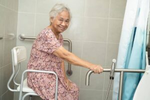 Senior woman safely using bathroom support bars to bathe with assistance from Ace Home Care