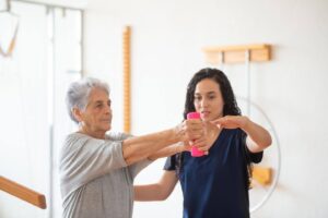 Senior working on strength exercises with caregiver support as Ace Home Care discusses the slow loss of physical independence with aging