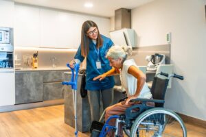 Caregiver helping a senior safely transfer from a wheelchair during recovery at home with support from Ace Home Care