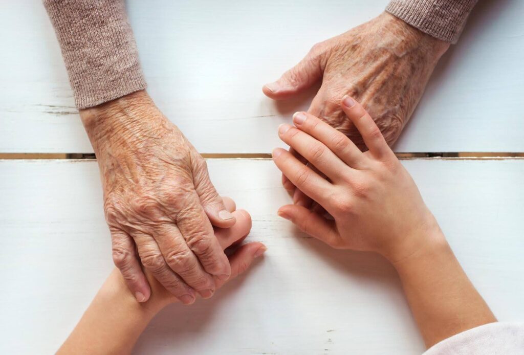 Caregiver holding an older adult’s hands, illustrating support and healthy aging while addressing muscle loss after age 65 with compassionate care from Ace Home Care