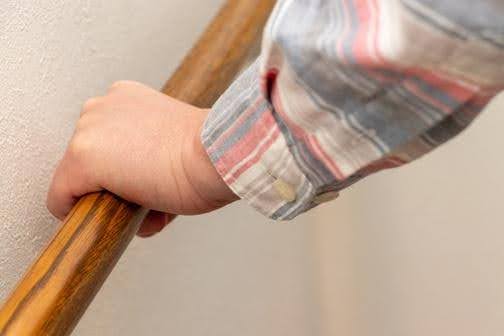 Senior gripping a wooden handrail, illustrating how grip strength can reflect overall health, mobility, and independence in older adults supported by Ace Home Care.