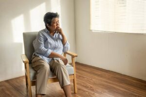 Aging parent living alone and sitting quietly at home, highlighting the importance of regular family check-ins and support from Ace Home Care.