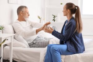 Caregiver offering assistance to an older adult at home as he hesitates to accept help from Ace Home Care.