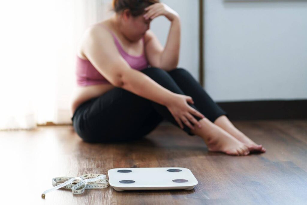Older adult concerned about weight loss sitting near a scale, highlighting why unexplained weight changes in seniors should not be ignored.