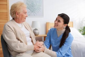 Home care caregiver holding an elderly woman's hands and offering compassionate support, highlighting the growing demand for senior care and home care franchise opportunities.