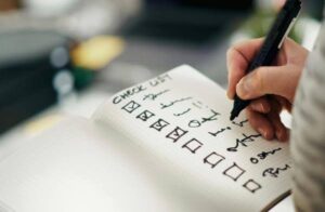 Person writing a checklist of daily tasks and responsibilities to help an aging parent manage everyday needs at home.