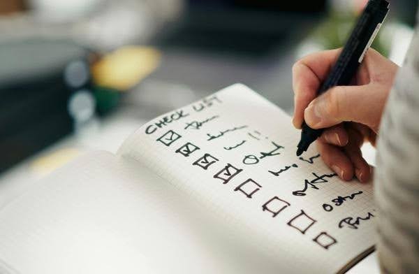 Person writing a checklist of daily tasks and responsibilities to help an aging parent manage everyday needs at home.