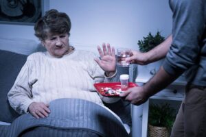 An aging parent refusing offered medication and water at home, highlighting the challenges families face when seniors resist help with everyday activities.
