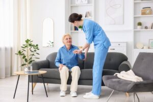 Caregiver assisting an elderly woman from a sofa, highlighting how personalized home care schedules support an aging parent's daily needs and independence.
