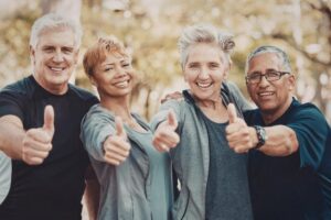 Group of smiling older adults giving thumbs up outdoors, highlighting the growing senior population and community demand for non-medical home care services and business opportunities.