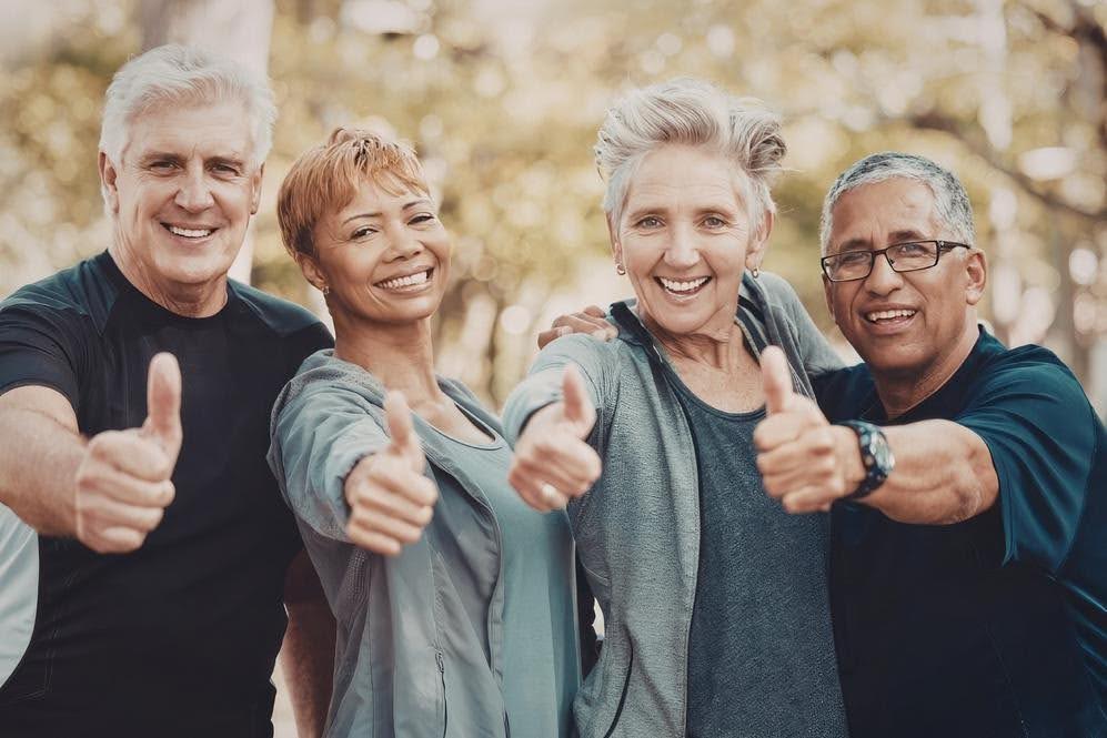 Group of smiling older adults giving thumbs up outdoors, highlighting the growing senior population and community demand for non-medical home care services and business opportunities.