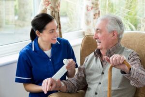 Home care caregiver assisting an elderly man with a bandage while assessing his daily care needs and comfort at home.